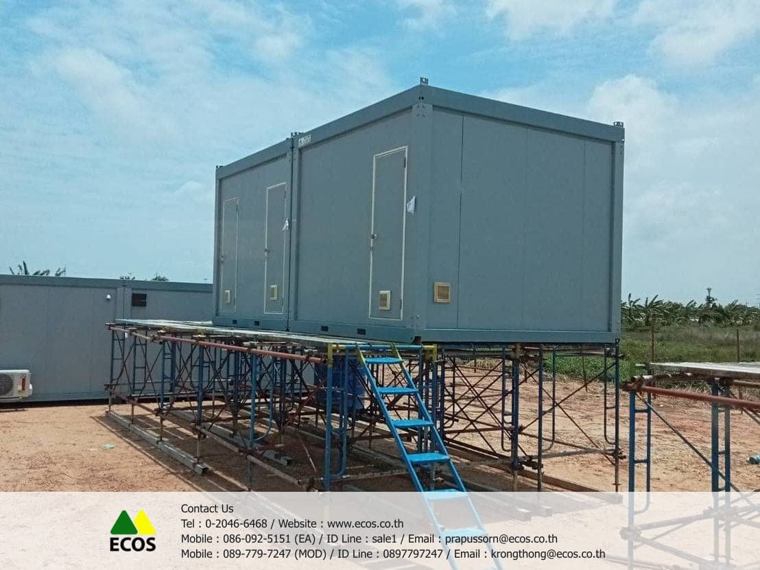 ตู้ห้องน้ำสำเร็จรูป WT-Toilet ขนาด 3x3 เมตร ยกขึ้นตั้งบนนั่งร้านที่ไซต์งาน เห็นประตูห้องน้ำเรียงกันและช่องระบายอากาศใต้ประตูแต่ละบาน มีบันไดเหล็กขึ้นด้านหน้า