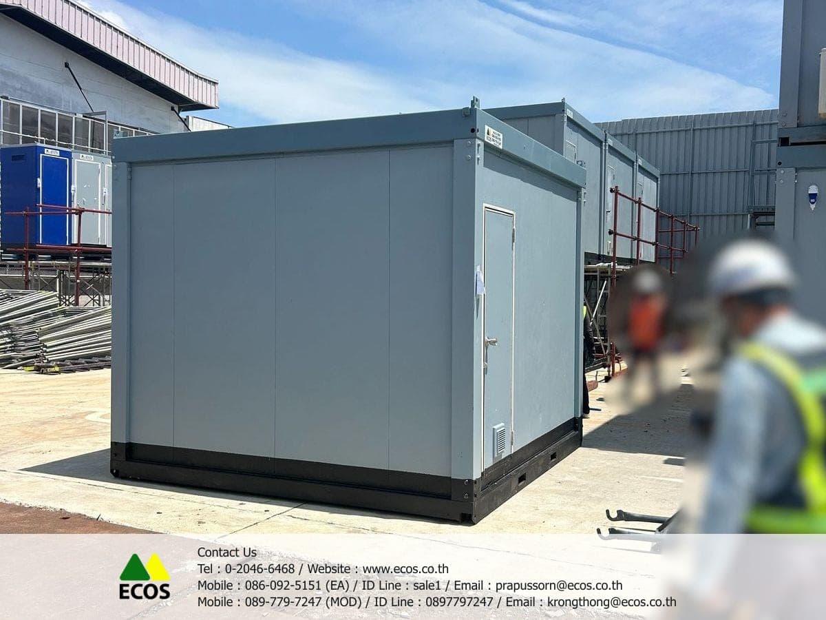 The WT-Toilet 3 x 3 standing on a concrete slab in the yard, seen from an angle: the long wall, the end door and the black base frame