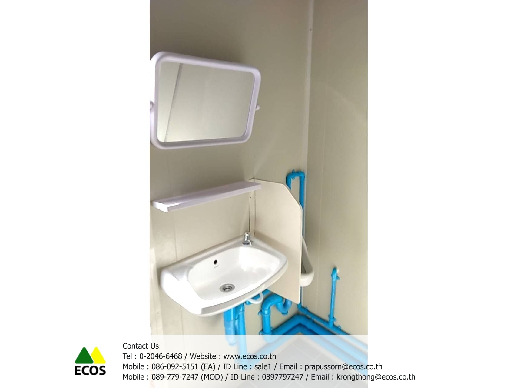 อ่างล้างมือภายใน WT-Toilet พร้อมก๊อกน้ำ กระจกเงา และชั้นวางของเหนืออ่าง เดินท่อ PVC สีฟ้าไว้ให้เห็นเพื่อให้ซ่อมบำรุงได้ง่าย